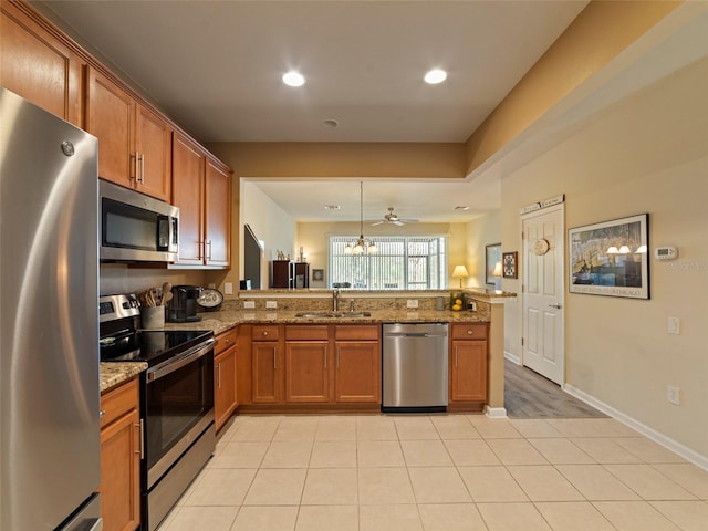 kitchen with pendant lighting, sink, stone counters, appliances with stainless steel finishes, and kitchen peninsula