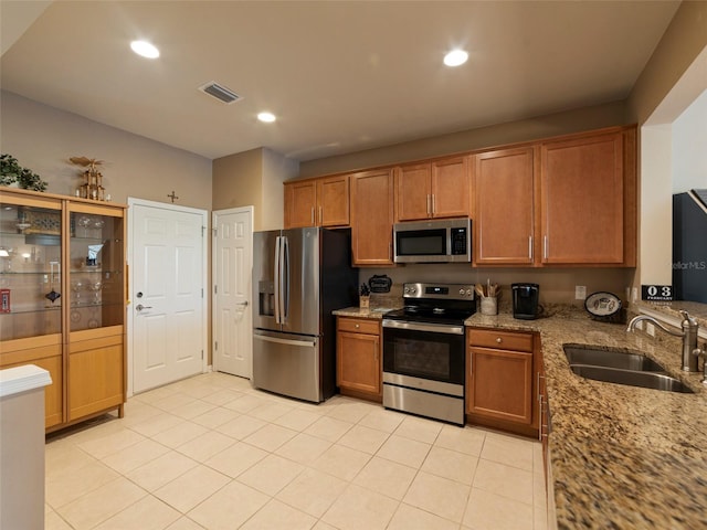 kitchen with light stone counters, stainless steel appliances, light tile patterned flooring, and sink