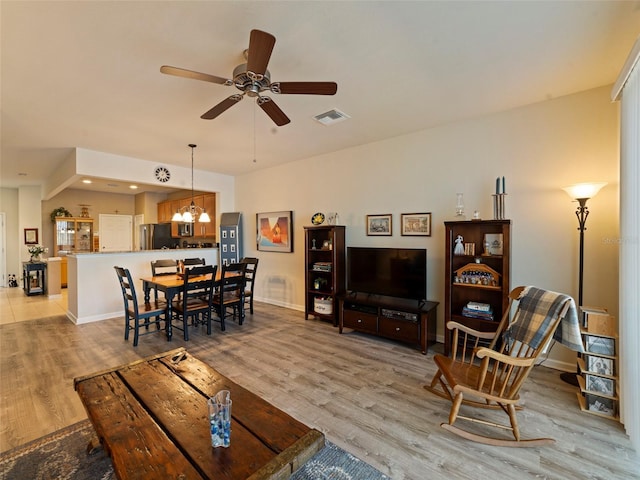 living room with ceiling fan with notable chandelier and light wood-type flooring