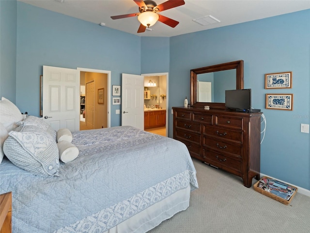 bedroom with ensuite bath, vaulted ceiling, light colored carpet, and ceiling fan