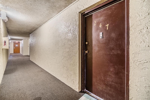 corridor with carpet flooring and a textured ceiling