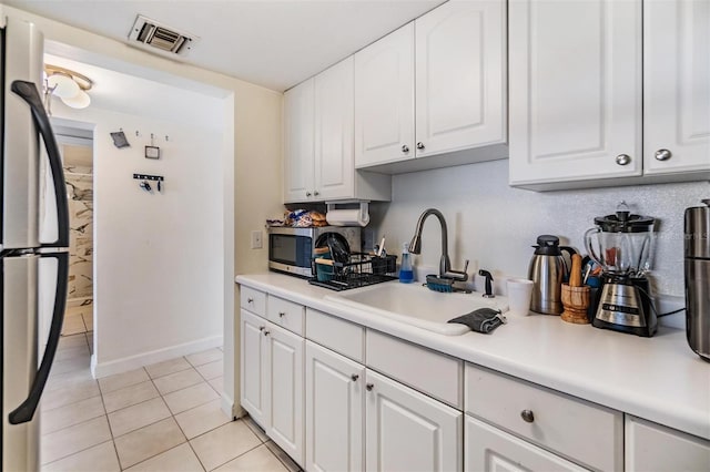 kitchen featuring light tile patterned flooring, appliances with stainless steel finishes, sink, and white cabinets