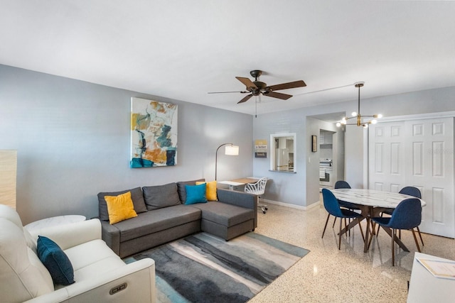 living room featuring ceiling fan with notable chandelier