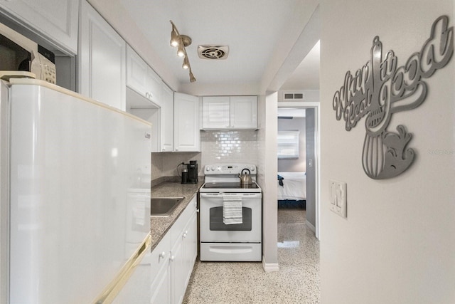 kitchen with sink, white appliances, white cabinetry, tasteful backsplash, and dark stone counters