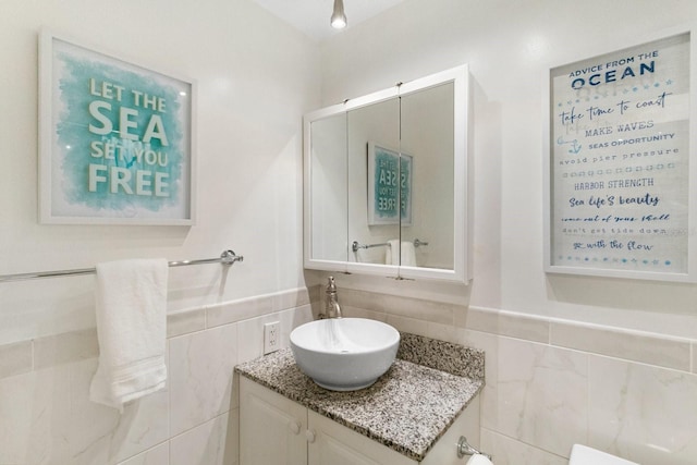 bathroom featuring vanity and tile walls