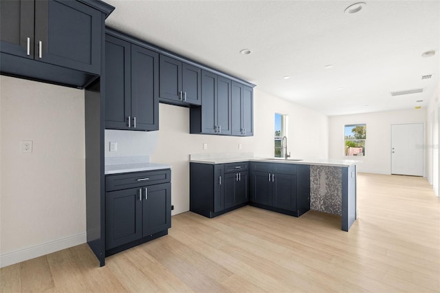 kitchen with sink, kitchen peninsula, and light hardwood / wood-style flooring