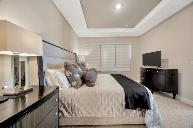 bedroom with a tray ceiling and light carpet