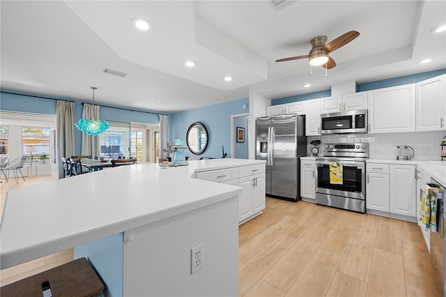 kitchen featuring stainless steel appliances, white cabinetry, a center island, and pendant lighting