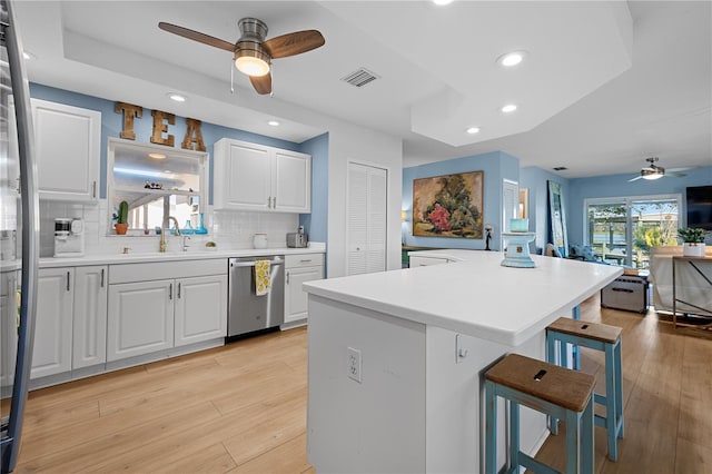 kitchen featuring sink, a kitchen breakfast bar, a center island, white cabinets, and stainless steel dishwasher