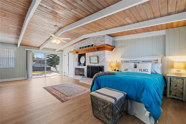 bedroom with vaulted ceiling with beams, access to exterior, ceiling fan, a brick fireplace, and light wood-type flooring