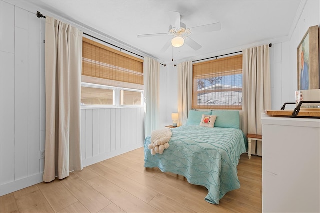 bedroom with ceiling fan, multiple windows, and light hardwood / wood-style flooring