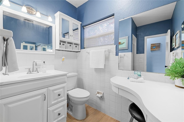 bathroom featuring tile walls, vanity, wood-type flooring, and toilet