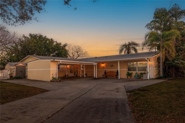 ranch-style home featuring a carport and a shed