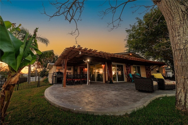 back house at dusk with a pergola and a patio