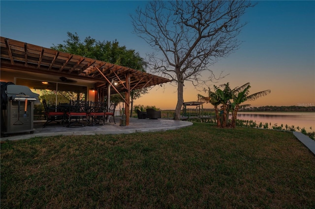 yard at dusk featuring a water view and a patio area