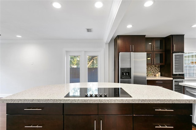 kitchen featuring crown molding, stainless steel appliances, a center island, dark brown cabinetry, and tasteful backsplash