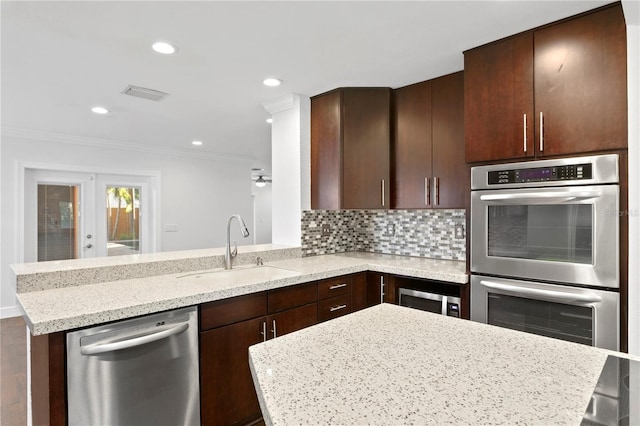 kitchen with sink, light stone counters, tasteful backsplash, a kitchen island, and stainless steel appliances