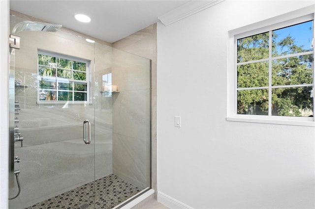 bathroom with an enclosed shower, ornamental molding, and a healthy amount of sunlight