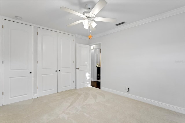 unfurnished bedroom with crown molding, a closet, ceiling fan, and light carpet