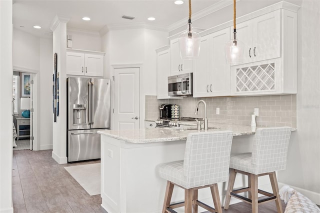 kitchen featuring sink, appliances with stainless steel finishes, light stone countertops, white cabinets, and a kitchen bar