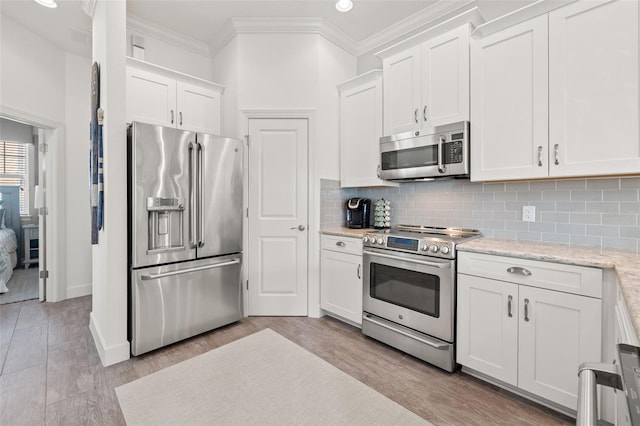 kitchen featuring tasteful backsplash, appliances with stainless steel finishes, crown molding, and white cabinets