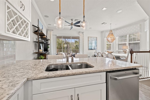 kitchen featuring hanging light fixtures, stainless steel dishwasher, ornamental molding, decorative backsplash, and white cabinets