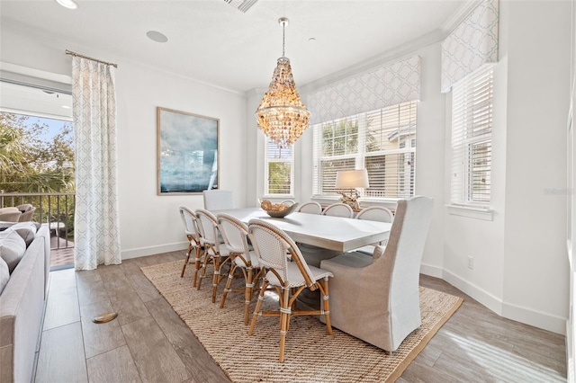 dining room with a notable chandelier, crown molding, and hardwood / wood-style flooring