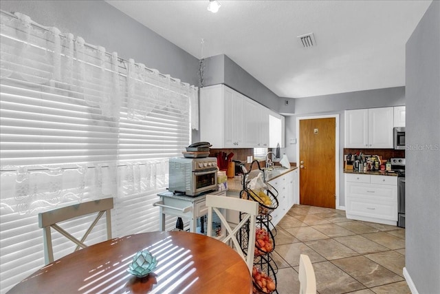 kitchen featuring stainless steel appliances, white cabinetry, sink, and light tile patterned floors