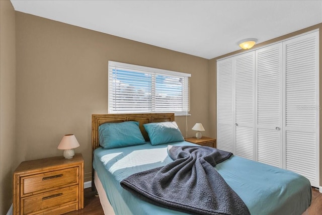 bedroom with dark hardwood / wood-style floors and a closet