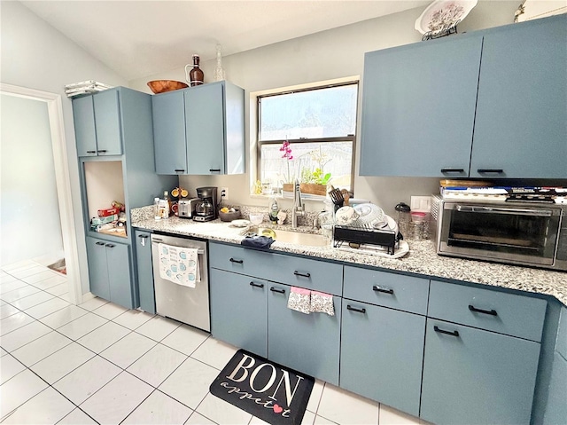 kitchen with blue cabinets, lofted ceiling, sink, stainless steel dishwasher, and light tile patterned floors