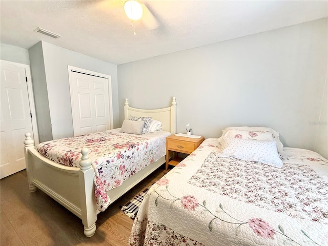 bedroom featuring dark wood-type flooring, ceiling fan, a closet, and a textured ceiling