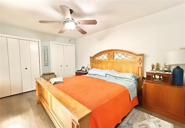 bedroom with ceiling fan, wood-type flooring, and multiple closets