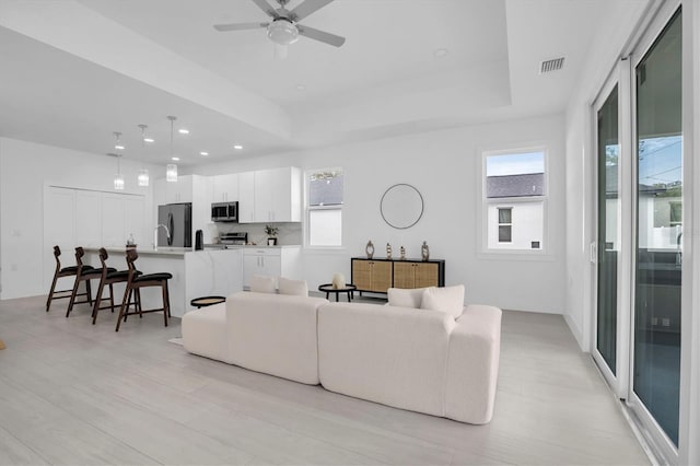 living room with ceiling fan and a tray ceiling