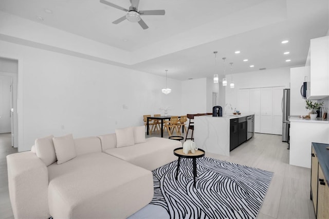 living room featuring sink, light hardwood / wood-style flooring, and ceiling fan