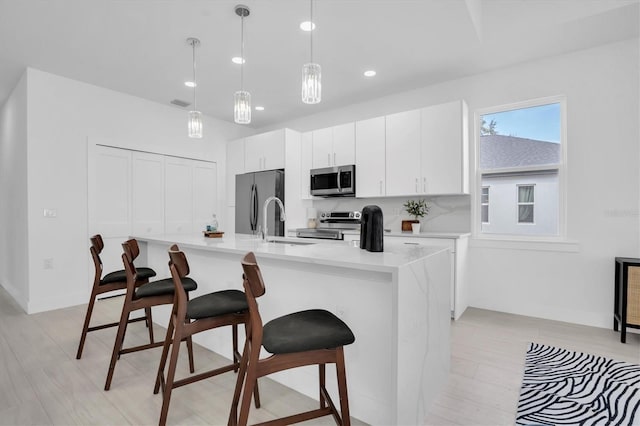 kitchen featuring white cabinetry, appliances with stainless steel finishes, a breakfast bar area, and pendant lighting