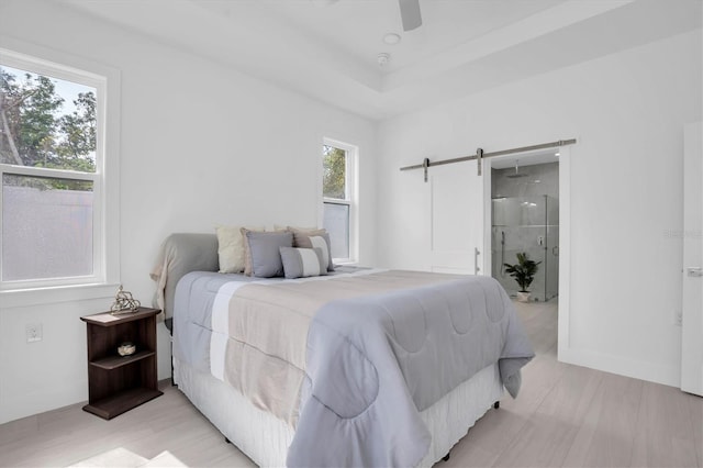 bedroom featuring a raised ceiling, a barn door, and ceiling fan