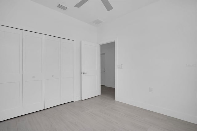 unfurnished bedroom featuring light hardwood / wood-style floors, ceiling fan, and a closet