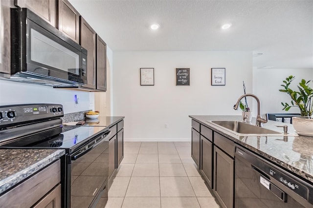 kitchen with sink, dark stone countertops, light tile patterned floors, black appliances, and dark brown cabinets