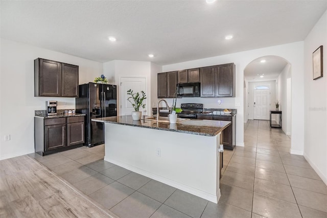 kitchen featuring a sink, dark stone counters, dark brown cabinetry, and black appliances