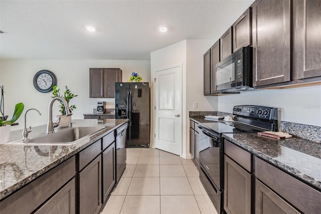 kitchen featuring black appliances, a sink, dark stone counters, light tile patterned floors, and dark brown cabinets