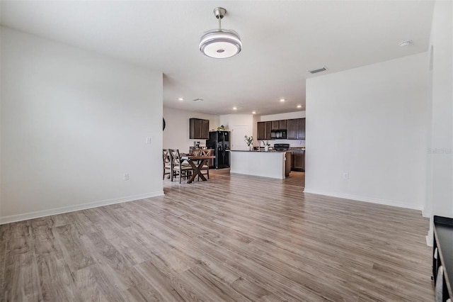 living room with recessed lighting, visible vents, baseboards, and light wood finished floors