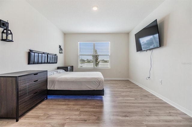 bedroom featuring light wood finished floors and baseboards