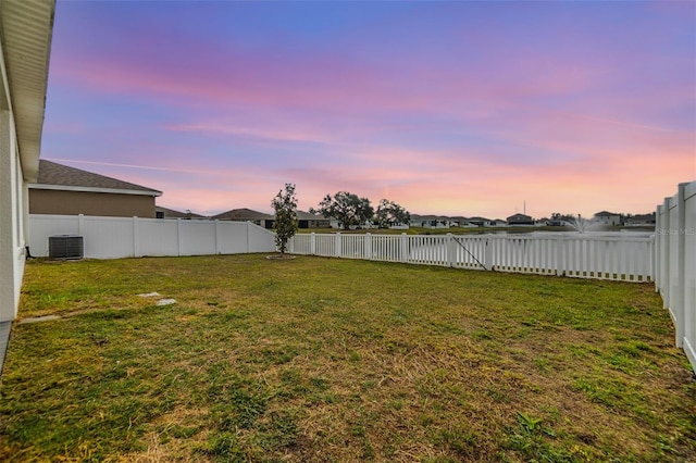 yard at dusk featuring central air condition unit and a fenced backyard