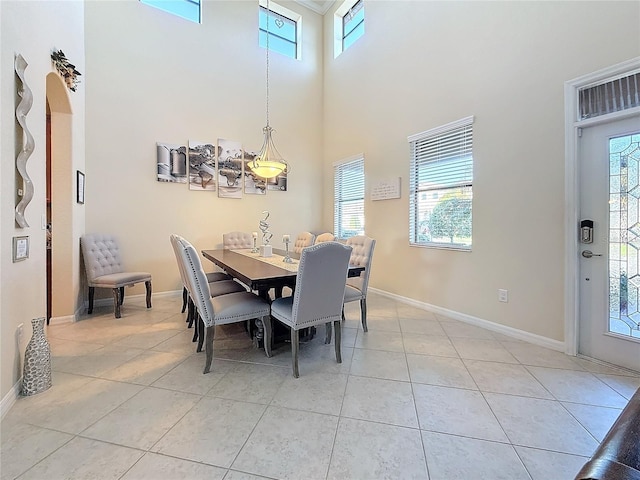 dining space with light tile patterned floors, plenty of natural light, and a high ceiling