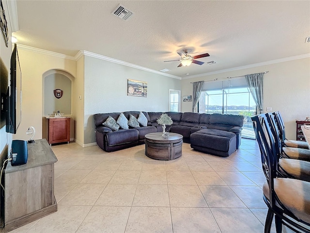 living room featuring ornamental molding, light tile patterned floors, ceiling fan, and a textured ceiling