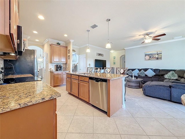 kitchen with pendant lighting, sink, light tile patterned floors, appliances with stainless steel finishes, and an island with sink