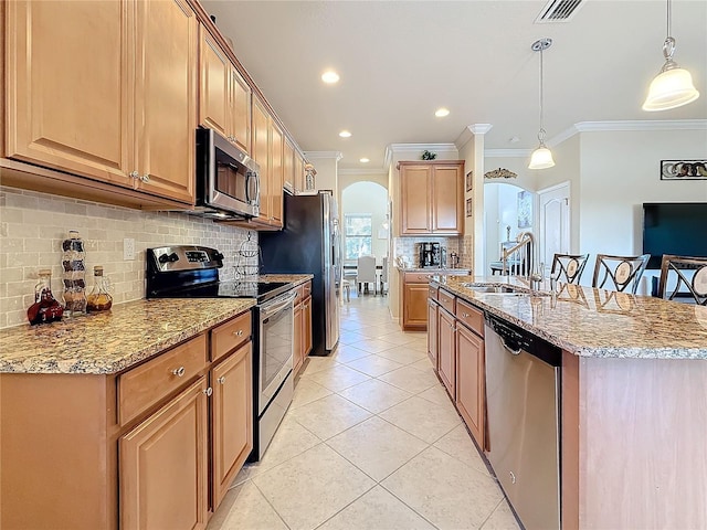 kitchen featuring sink, light tile patterned floors, stainless steel appliances, light stone counters, and decorative light fixtures