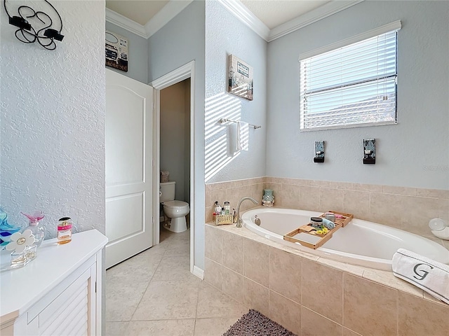 bathroom featuring tile patterned floors, ornamental molding, toilet, and tiled bath