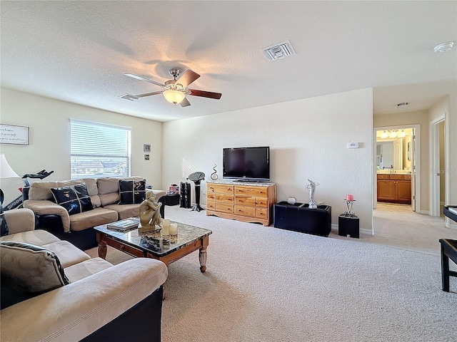 living room with ceiling fan, light carpet, and a textured ceiling