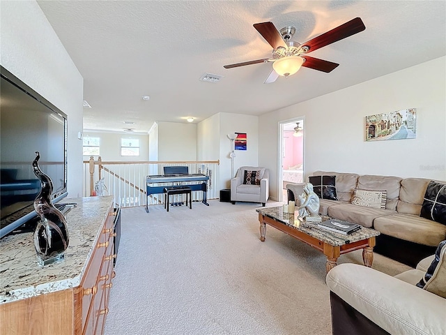 carpeted living room featuring ceiling fan and a textured ceiling